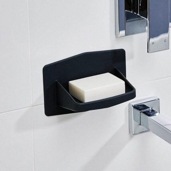 Close up of a soap holder next to a shower valve and faucet.