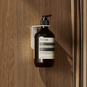 A brown soap bottle mounted on a metal soap dispenser attached to a wall