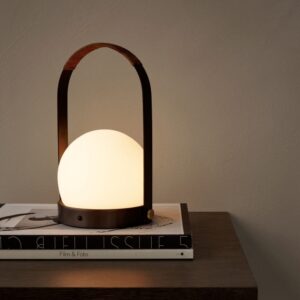 A portable hand-carry round shaped lamp on a stack of books.