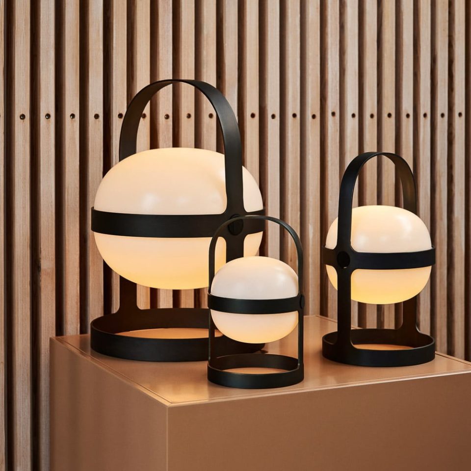 All three of ROSENDAHL's Soft Spot Solar lamps. Each is switched on and glowing a soft golden yellow colour, illuminating a nude-peach coloured plinth.