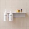 Perspective view of the White DESIGNSTUFF Shelf w/ Dual Soap Dispenser Holder 40cm in a bathroom with white tiles
