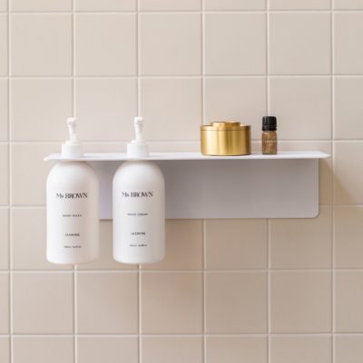 Perspective view of the White DESIGNSTUFF Shelf w/ Dual Soap Dispenser Holder 40cm in a bathroom with white tiles