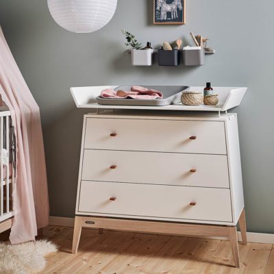 LEANDER Luna Dresser Changing Unit, White in a nursery with a blue wall behind it