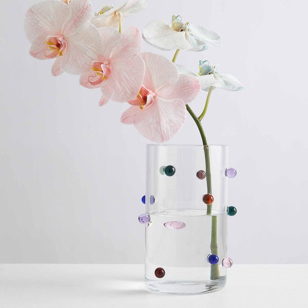 A clear vase encrusted with small, ball-shaped jewels and with orchids inside it.