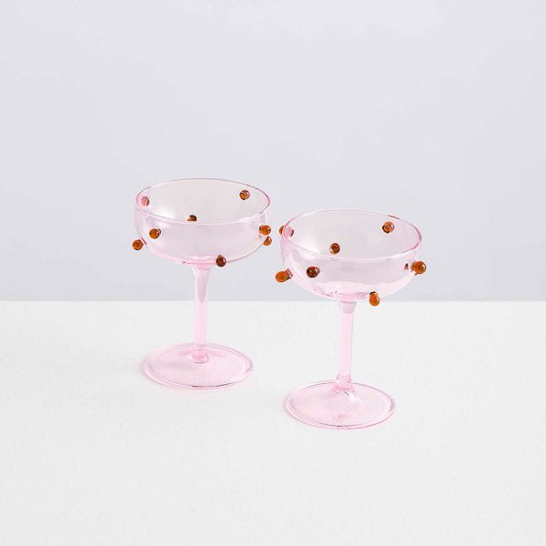 Two pink, bead-encrusted champagne glasses on top of a table