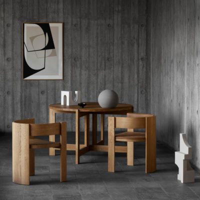 Collector dining table and chair by Kristina Dam Studio with sculptures on the floor and dining table. A large framed print is hung on the wall.