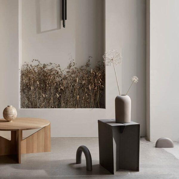 Kristina Dam Studio oak table and a stoneware vase with wall framed dried flowers in the background.