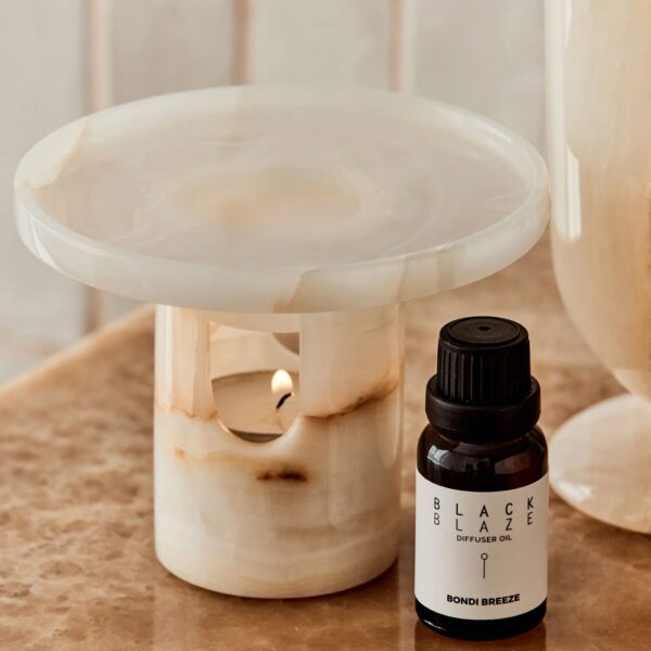 A cylinder-shaped oil diffuser with a round tray on top placed next to an oil bottle.