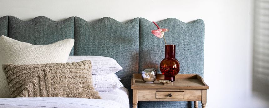 Styled in the bedroom of Bea Lambos's home is Citta and ferm Living Cushion on a bed, next to a side table holding the Maison Balzac Amber Vase, Eva Solo night light, and ferm Living Oyster bowl