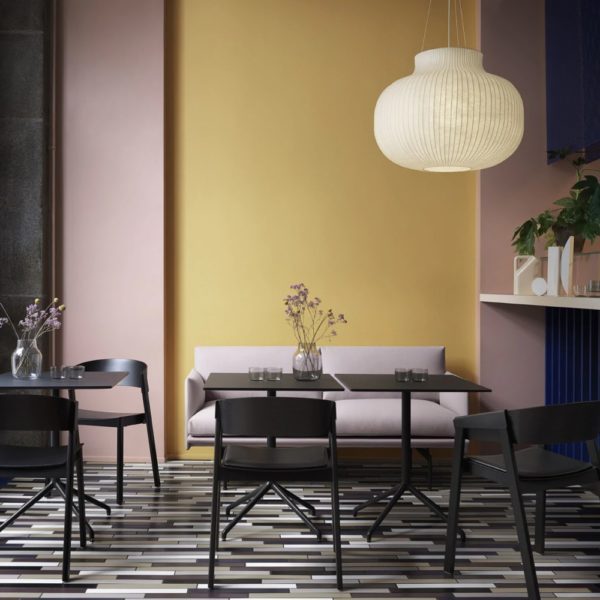 White MUUTO Strand Pendant Lamp hanging above dining table in a restaurant with mustard and mauve painted walls