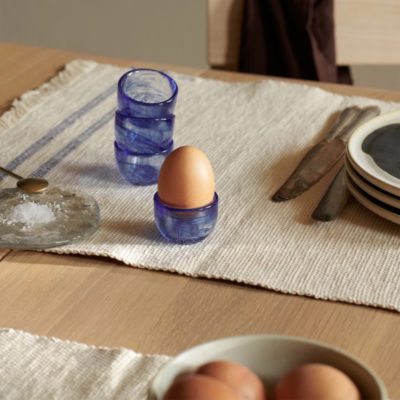 ferm LIVING Tinta Egg Cups, Blue Set of 4 on a dining table with an egg in the cup