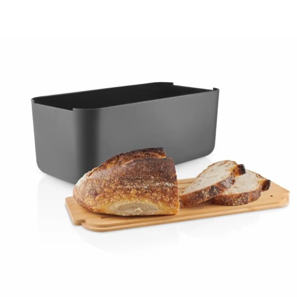 Studio lighting, perspective view of a rectangular-shaped metal bread container with a pieces of bread placed on top of its bamboo lid