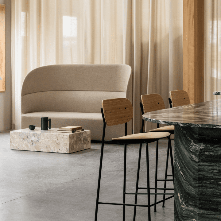 This photo illustrates the 2023 design trend of Natural Materials, and features MENU's marble plinth in a beige Breccia stone, set in a restaurant environment.