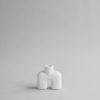 Two legged white vase with cylindrical stemmed opening shot in Studio setting