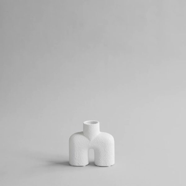 Two legged white vase with cylindrical stemmed opening shot in Studio setting