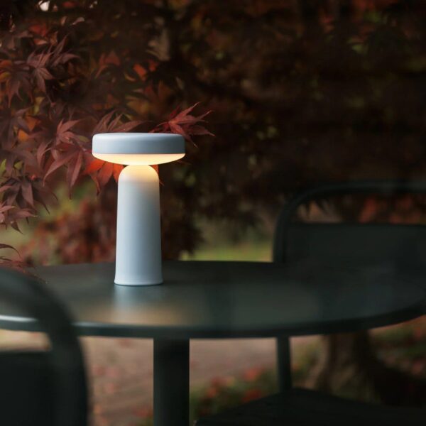 a light blue lamp sitting on a black table in an outdoor setting