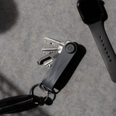 Natural light, dark background, top view of a black, rubber-made key organiser with keys and tools exposed.