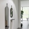 Shot of a room with a hanging mirror mounted beside a vertically hung bulletin board on a lit, grey wall.