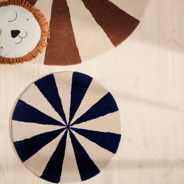 Natural lighting, white background, top view of a circle-shaped kids' rug with alternating blue and off-white slicing patterns.