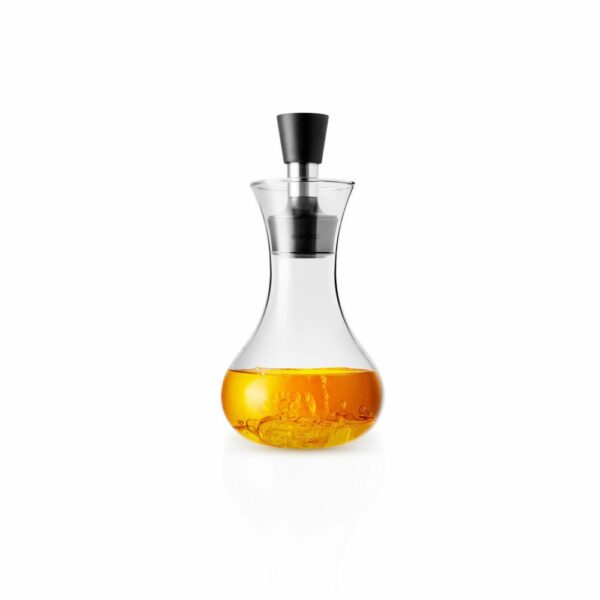 White background, studio lighting, perspective view of a transparent, glass dressing shaker filled with a clear orange dressing, and with a black silicone fixed on its spout.
