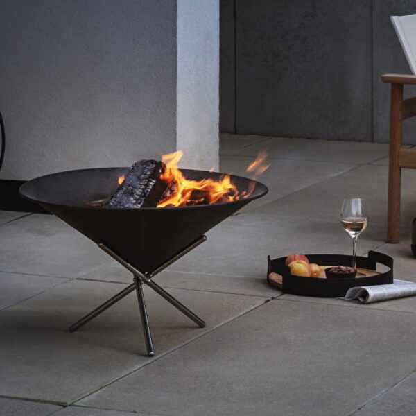 Natural light, perspective view of a steel, cone-shaped fire pit with smouldering wood
