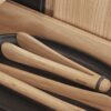Natural light, close up, perspective view of wooden kitchen tongs laid inside a pull-out drawer.
