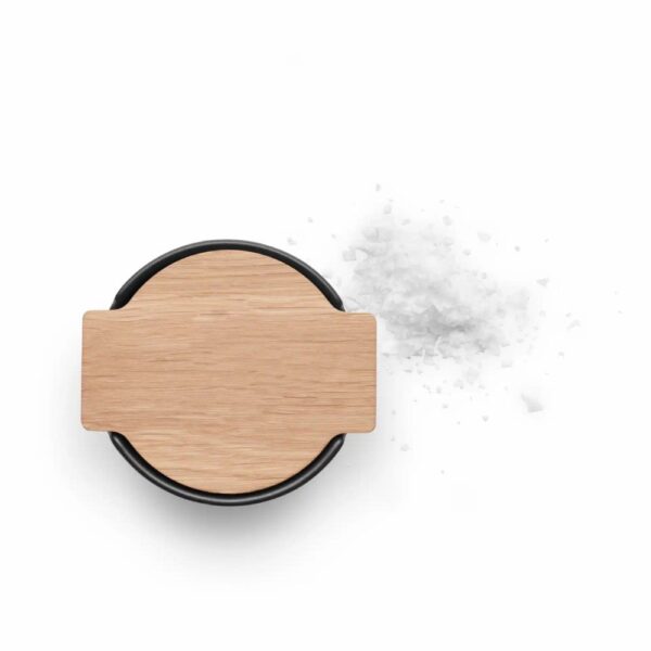 White background, studio lighting, top view of a black, steel canister-shaped salt cellar with a bamboo lid.