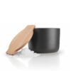 White background, studio lighting, perspective view of a black, steel canister-shaped salt cellar with a bamboo lid.