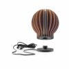 White background, studio lighting, perspective view of bulb-shaped, wooden, dark oak lamp with its charging base and wire placed beneath.