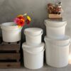 Natural lighting, studio shot of 5 white, different sized storage and garden bins with some stacked on top of each other and on a crate.