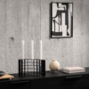 Mesh candle holder on a table with a monochrome wall art on concrete wall.