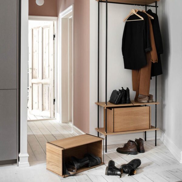 Natural light, perspective view, editorial style photo of a room with wooden storage boxes and a wardrobe with hanging clothes.
