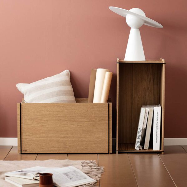 Natural light, perspective view, editorial style photo of rectangular wooden storage boxes with pillows inside and a planet-shaped lamp placed on top of the box's side.