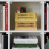 A stack of colour crate storage box in yellow on book shelf