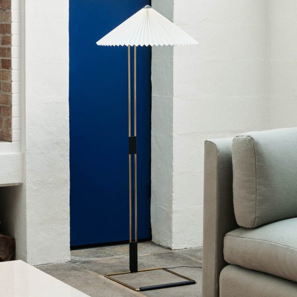 Matin Floor Lamp with polished brass finish and white shade in a lounge room.
