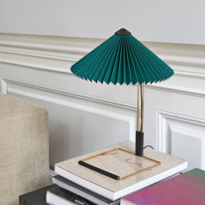 Matin table lamp with polished brass finish and green shade in a lounge room.