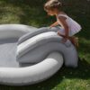 A little girl is playing on the inflatable outdoor kids rainbow pool with a slide by Konges Sloejd.