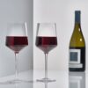 Set of 2 mouth-blown Rocks red wine glasses by Zone Denmark and a bottle of wine.