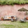 ferm LIVING Lull Umbrella in Military Green contrasting pink garden wall