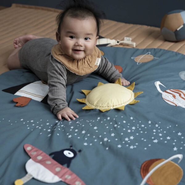 A baby on an activity play and crawling blanket Planetary in green.