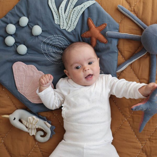 A baby on a travel size activity play and crawling blanket Underwater in green.