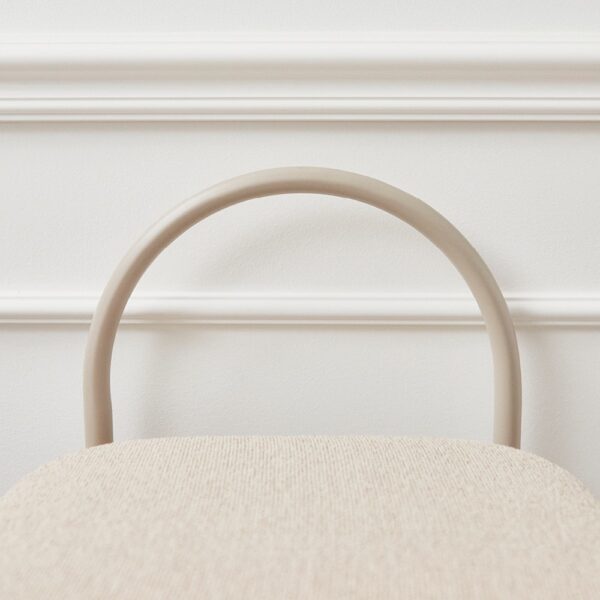 Natural lighting, close up view of a stool's arch-shaped backrest.