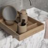 A wooden tray filled with toiletries placed on top of a marble counter.