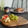 Deborah serving tray made from marble in brown with cheese on fruits on a dining table.