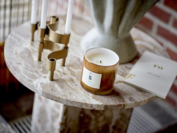 A scented candle and a candle holder on Jasmia brown marble side table.