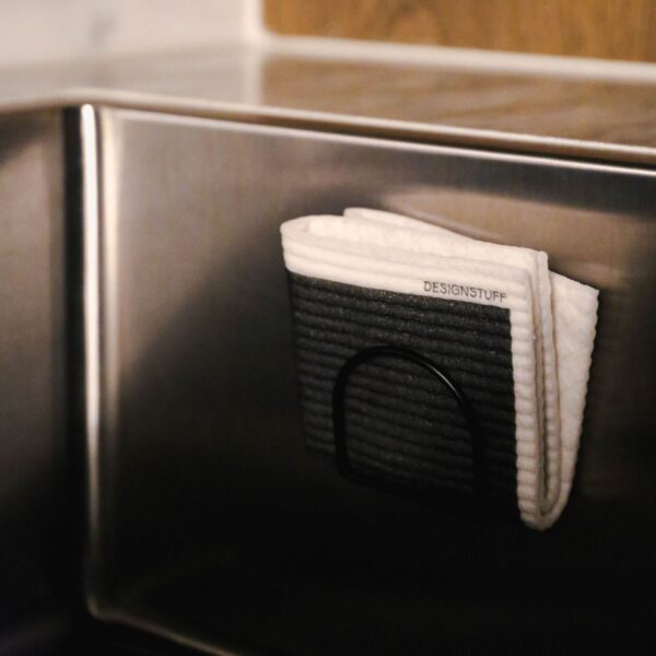 Folded black dishcloth in a sink sponge holder