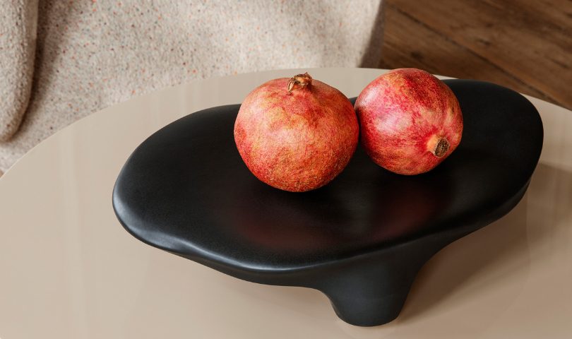 the ferm LIVING Esca Piece with two pomegranates resting on it.