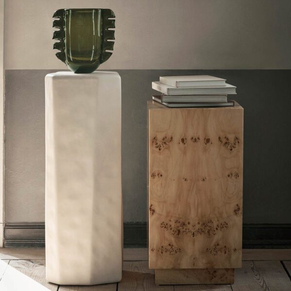 A hand-made Alas vase on a pedestal table has a unique and ornamental shapes in moss green.