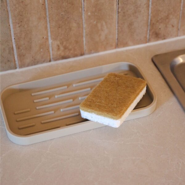 Natural lighting, perspective view of a sponge placed on a kitchen sink.