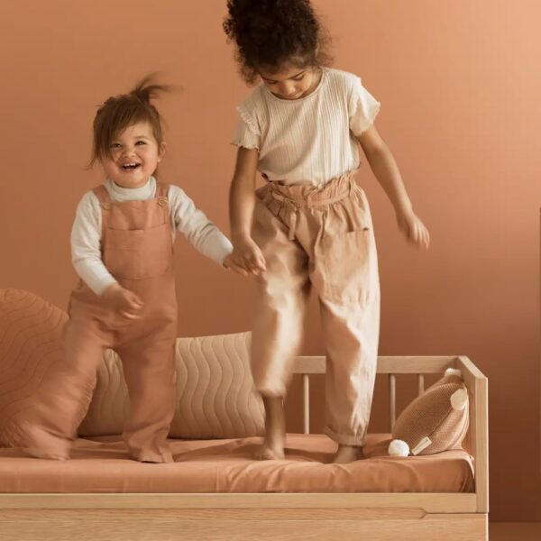 Studio lighting, perspective view of two kids playing on a wooden bed frame.